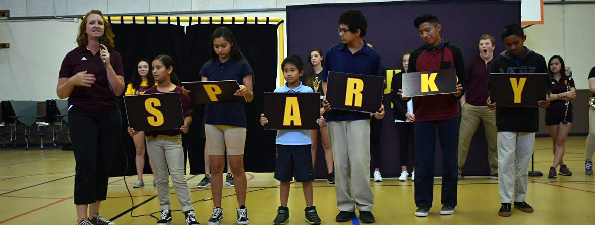 Teacher with microphone along with students holding up SPARKY letters