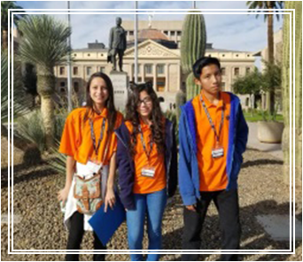 Three Aguila Middle school students wearing their orange t-shirts posing for a picture outside
