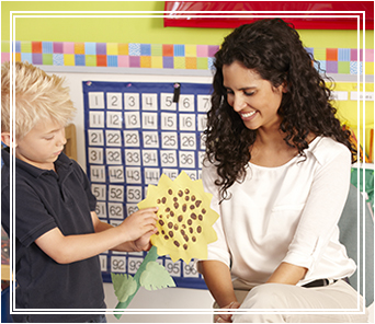 Student handing a paper flower to a teacher